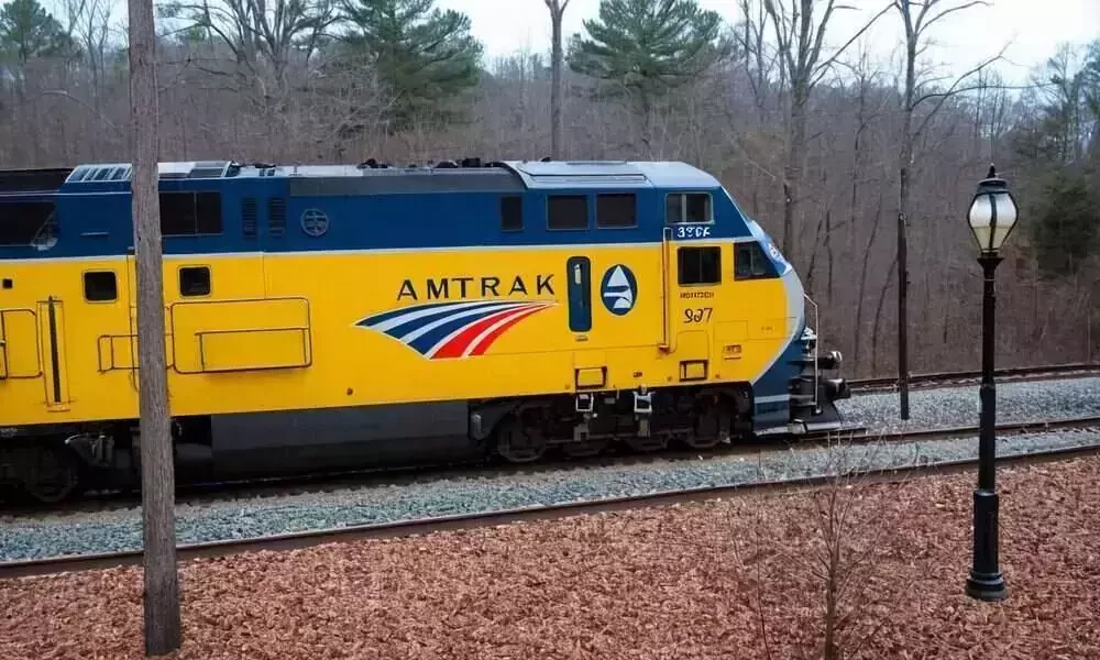 yellow and blue Amtrak train engine on the tracks
