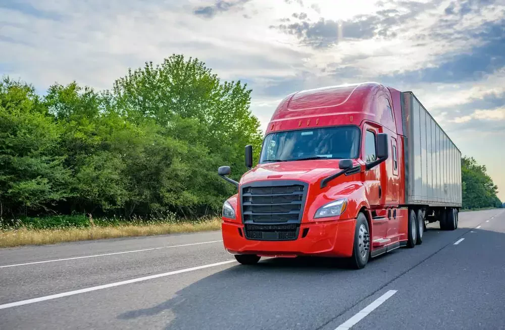 red truck driving under a cloudy sky