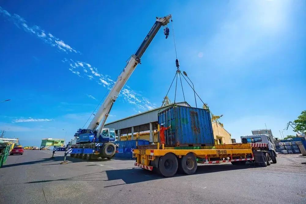 a crane lifts a large container onto a truck