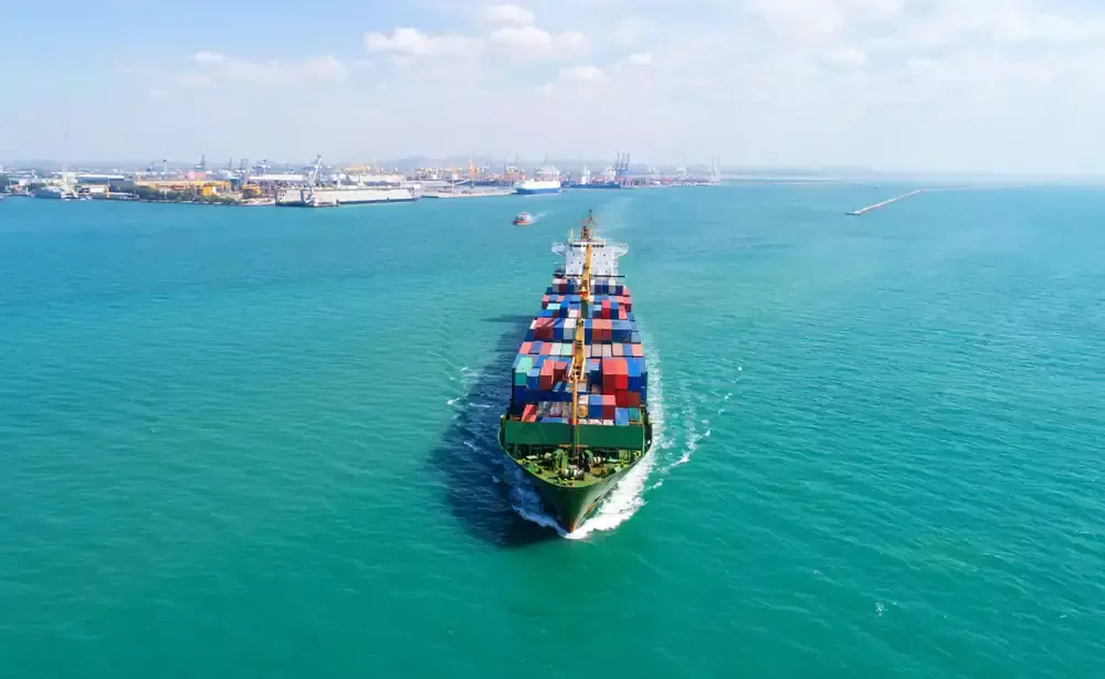cargo vessel sails from the port to the sea