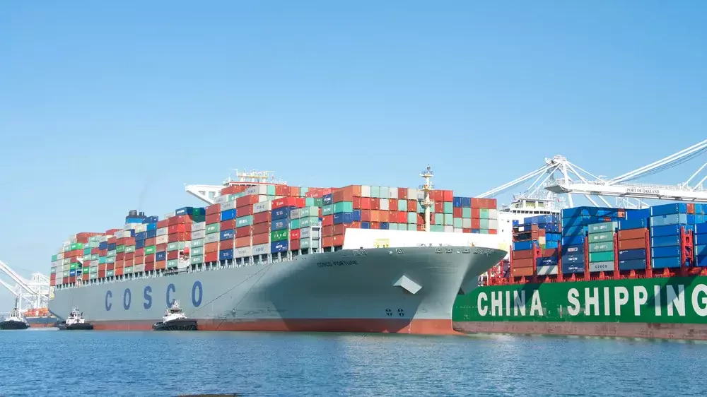 a large cargo vessel being guided by tugboats