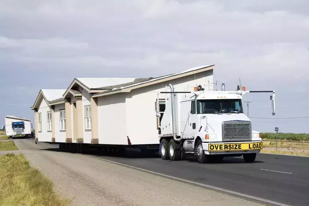 semi truck carrying a modular home on the road