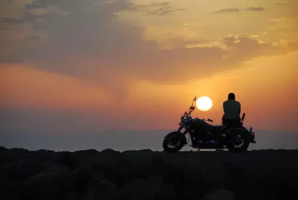 a man sitting on a bike at sunset