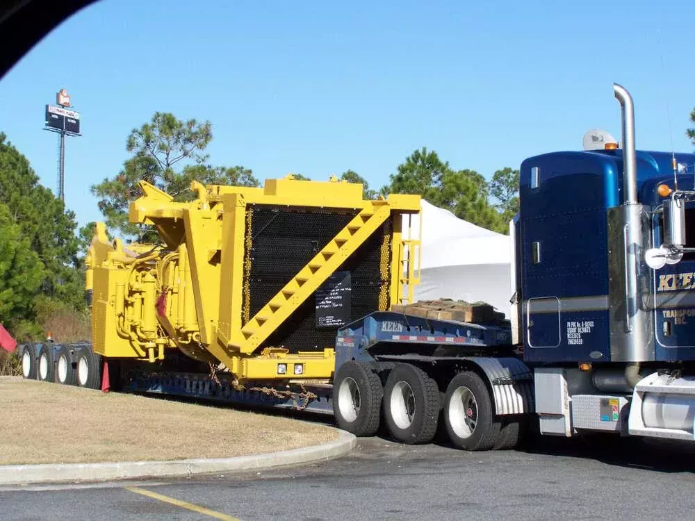 a smaller truck is towing a large yellow truck