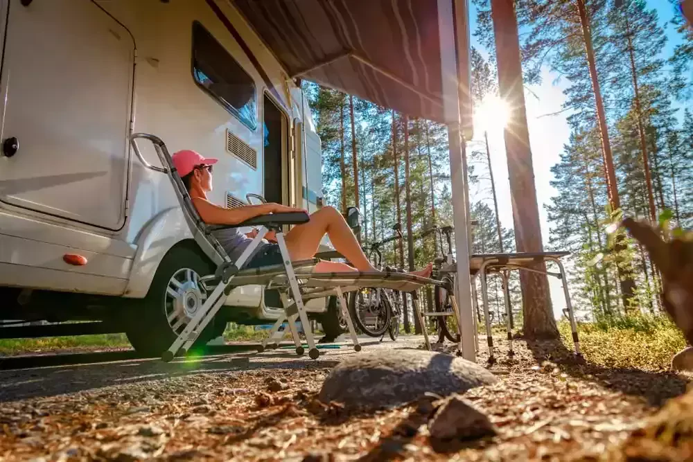 a woman relaxes in a chair beside her motorhome