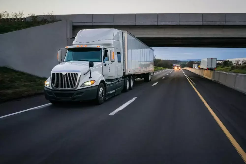 an enclosed hauler driving under the bridge