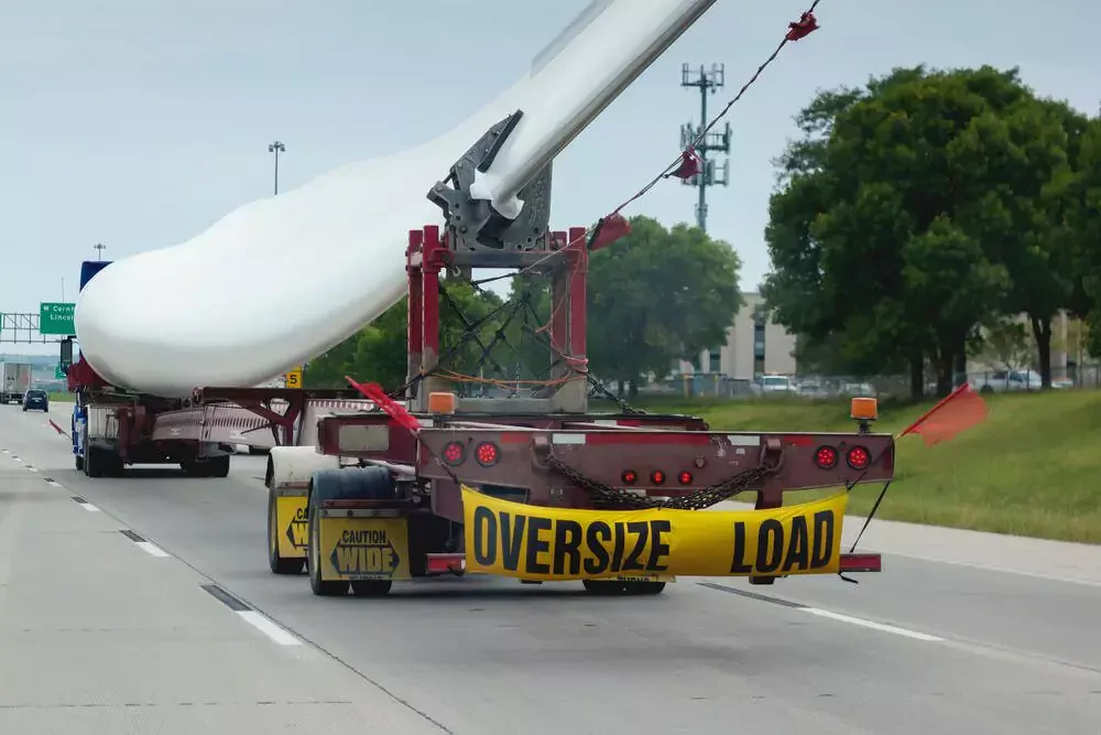 a truck transporting a large white air engine blade